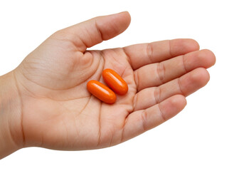 Isolated hand holding two orange softgel supplements, medicine, healthcare and treatment