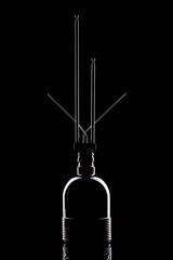 Still life with glass object and metal antenna on a black background