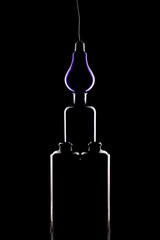 Still life with glass objects and light bulb on a black background