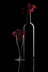 Still life with glass objects and red viburnum berries on a black background