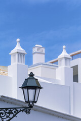 Ornate traditional Algarve chimney with decorative top structure on a white terrace in Faro, Portugal