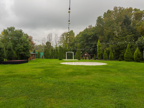 Outdoor wedding or event space with string lights and a circular stage on a green lawn