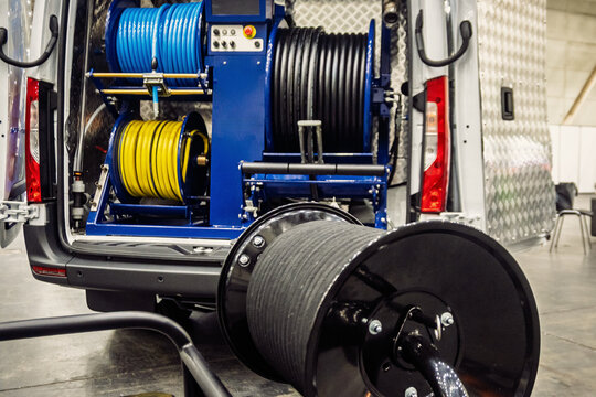 Professional drain cleaning equipment with hose reels (blue, yellow, black) inside a utility van, ready for industrial plumbing and maintenance.