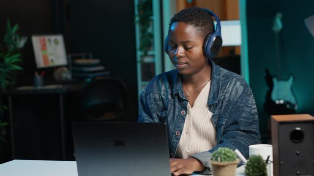 Cheerful woman relaxing at home by watching TV show on laptop using headphones. Happy person enjoying leisure time in apartment, consuming entertainment media content, camera A
