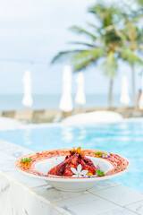 Gourmet seafood dish by luxurious poolside, tropical setting, vibrant colors, elegant plating, palm trees, ocean view, fine dining experience, summer vacation vibe.