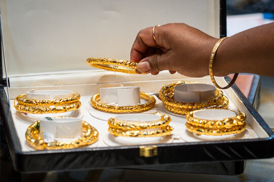 A customer picks a gold bangle at a jewelry store as festive demand surges despite a global rise in gold prices