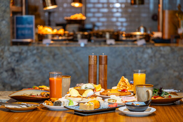 Luxurious breakfast buffet with waffles, pastries, fresh juice on restaurant table. Cozy hotel dining setting perfect for indulging in morning cuisine.