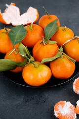 Orange tangerines in a bowl on a black background.
