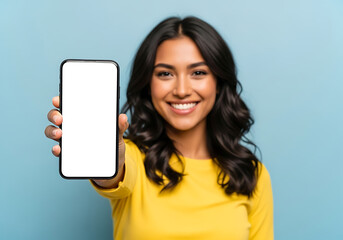 Fototapeta premium Young woman smiling while holding a smartphone with a blank white screen forward