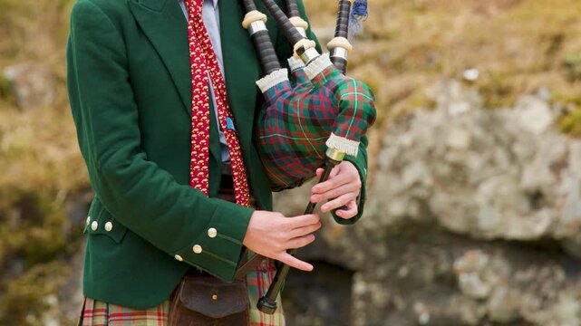 Scottish Bagpiper Playing Outdoors in Traditional Highland Attire