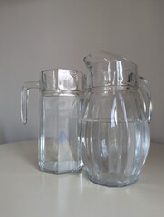 A decorative pair of transparent glass pitchers with unique designs, perfect for home styling concepts.