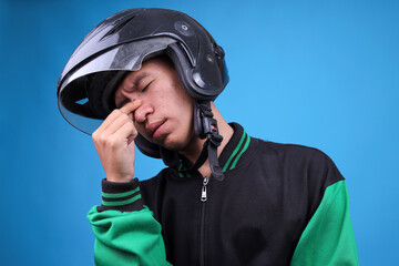 Asian Motorcycle Taxi Driver in Jacket and Helmet, Pinching Bridge of His Nose Showing Stress,...