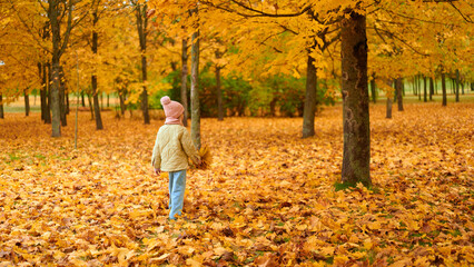 child in autumn park with colorful foliage, warm clothing, and cozy vibe. kid collects fallen...