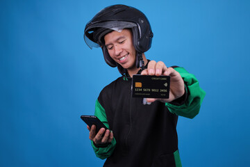 Smiling Young Indonesian Ojol Driver in Uniform Holding Out Credit Card While Operating His...
