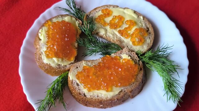 sandwich with butter and red caviar. The numbers 2026. A white plate on a red background. Dill sprigs. 2026 made of caviar on a sandwich. A woman's hand moves the plate.