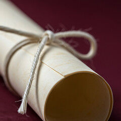 Classic Diploma Scroll Tied with Twine Against a Rich Red Background