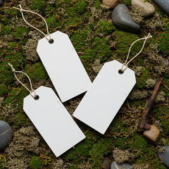Three blank white paper tags mockup lying on natural green moss background stones