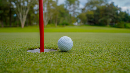 Golf ball is on a green lawn in a beautiful golf course with morning sunshine.