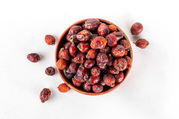 Bowl of dried rose hip berries on white background, healthy ingredient for cooking drinks, tea, healthy cocktails
