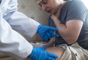 A man injects himself with adrenaline into his thigh during anaphylactic shock. First aid for allergies, emergency medical care for an allergic reaction. © Siniehina