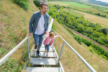 A father and daughters climb a steep staircase to the top of a hill.