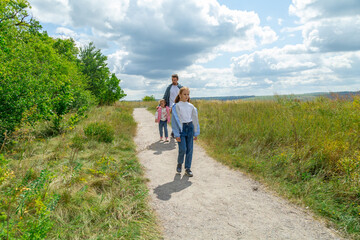Father and daughters walking in a field on a sunny day