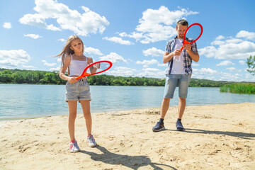 Dad and daughter playing beach tennis at the beach at sunny day