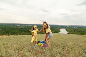 Mom and daughters having fun on the meadow to have a picnic to enjoy the summer day