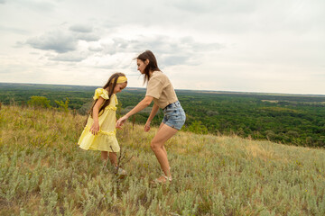 Mother and daughter as they walk through the field, having fun and laughing in summer day