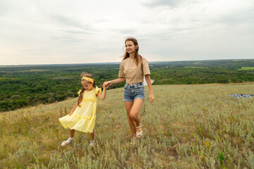 Mother and daughter as they walk through the field, having fun and laughing in summer day