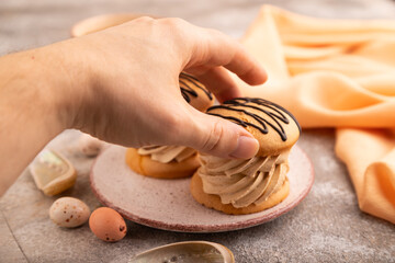 Caramel Cream Cakes with hand on brown concrete, cup of coffee, side view, close up, selective focus
