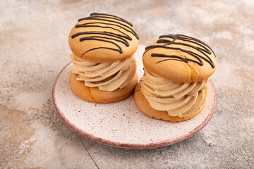 Caramel Cream Cakes on brown concrete, side view, close up