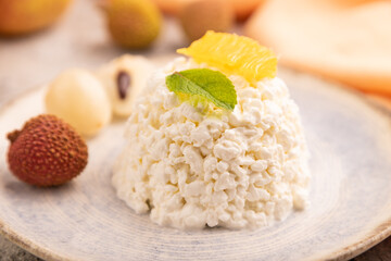White Сottage cheese, Curd, with orange and lychee on brown concrete and orange textile, side view, close up, selective focus