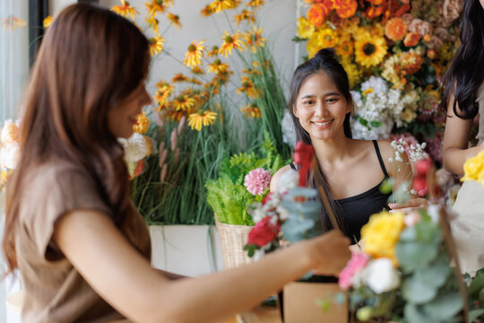 Young smiling florist arranging fresh flowers in shop - Powered by Adobe