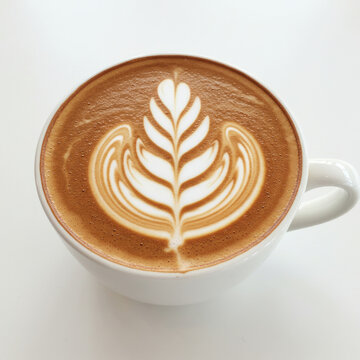 Close up shot of a latte art in a white ceramic cup on a white surface from above view