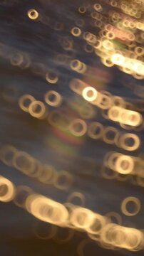 Abstract blurred sun glare on waves, orange lights on water surface, background.