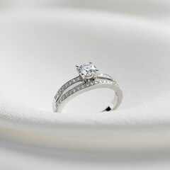 Close up of a silver engagement ring with diamonds on a white fabric background