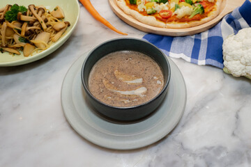 A close-up shot featuring a bowl of creamy mushroom soup, surrounded by other dishes