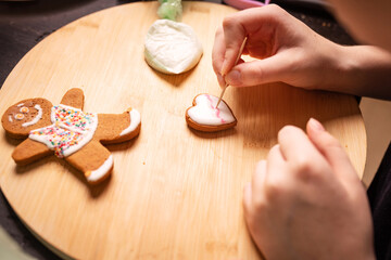 female hands decorating cookies, Christmas gingerbread cookies, rolling pin, baking tins in a home environment