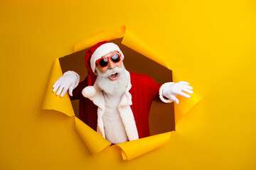 Charismatic Santa Claus bursting through yellow background exuding holiday joy, embodying the festive spirit