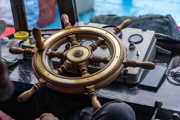 Close-up view of a traditional wooden boat wheel and control panel on a ferry operating in a mountainous region of Albania. © Christo