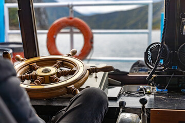 Boat steering wheel and control instruments inside the wheelhouse of a small passenger vessel on a mountain lake in northern Albania. © Christo