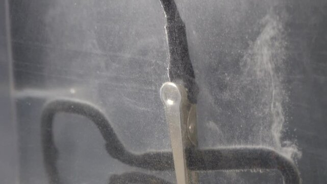 Negative wire attached to cathode produces hydrogen gas rising to top of electrolytic bath.