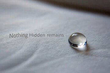 A clear glass droplet resting on a textured canvas surface