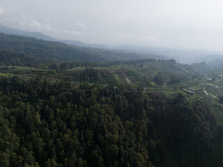 Naklejka premium Aerial view of green mountain landscape with clouds and blue sky.