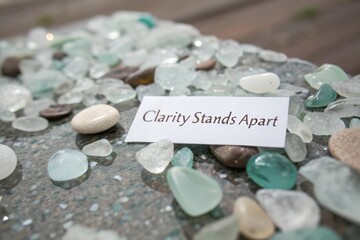 White card with Clarity Stands Apart text among sea glass and stones