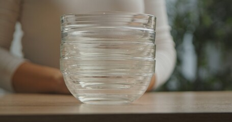 Close up of clear glass bowls stacked on a wooden table with a blurred background.