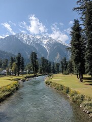 River flows through scenic valley in Pahalgam Kashmir India; landscape view of stream, mountains and trees on sunny day