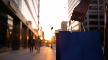 Urban shopper with paper bag at sunset — modern city retail vibe