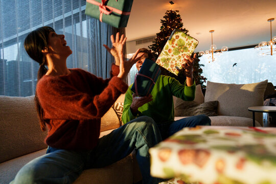 Couple exchanging gifts together joyfully at Christmas in living room